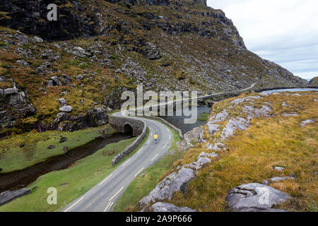 Frau zu Fuß durch den Fluss Loe, schmale Straße durch die Lücke der Dunloe Tal, in der macgillycuddy Reeks Berge, Irland, County Kerry gelegen. Stockfoto