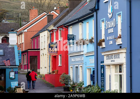 Paar huggung und gehen auf die Straße, in der bunten Gebäude, Cafe, Kneipen, Geschäfte im Küstenort Dingle, Kerry, Irland Stockfoto