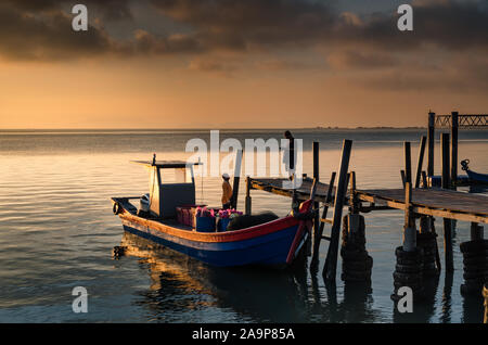 Silhouette des Fischers an einem traditionellen hölzernen Pier. Fischer beginnen in der Regel am Morgen zu arbeiten. Stockfoto