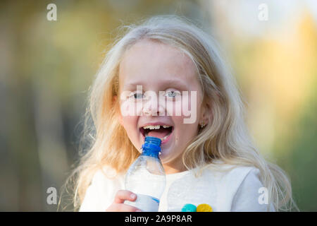 Fröhliches kleines Mädchen Kind blond Getränke Wasser aus einer Flasche Stockfoto