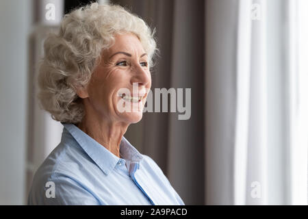 Gerne ältere Frau auf der Suche durch das Fenster träumen denken Gefühl der Hoffnung Stockfoto
