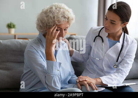 Junge weibliche Krankenschwester Arzt trösten trösten. traurige alte Großmutter patient Stockfoto