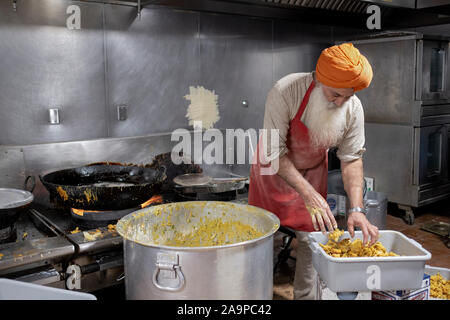 Ein Freiwilliger in einer langar, einem Sikh Tempel Küche, bereitet Pakora, ein frittiertes indische vegetarische. Snack. In South Richmond Hill, Queens, New York City. Stockfoto