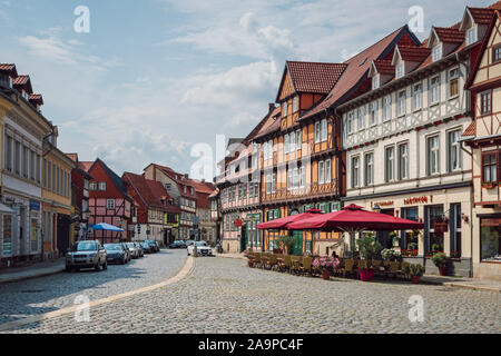 Blick auf einen gepflasterten Platz mit Restaurant im Freien in der mittelalterlichen Stadt mit traditionellen bunten Fachwerkhaus (Rahmen-) Häuser Quedlinburg. Stockfoto