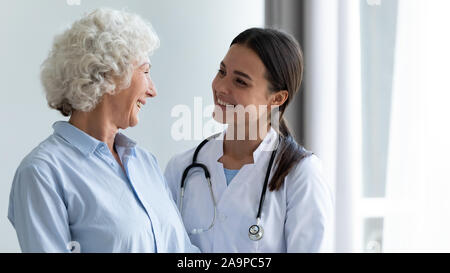 Lächelnden jungen weiblichen Krankenschwester Unterstützung glückliche Oma helfen in der Rehabilitation Stockfoto