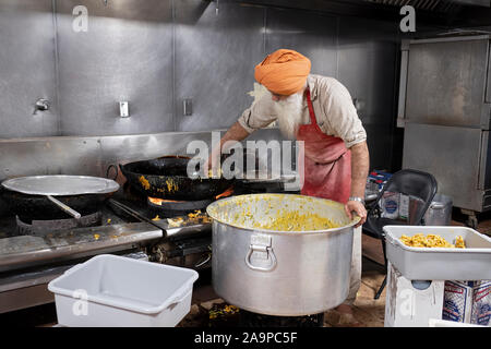 Ein Freiwilliger in einer langar, einem Sikh Tempel Küche, bereitet Pakora, ein frittiertes indische vegetarische. Snack. In South Richmond Hill, Queens, New York City. Stockfoto