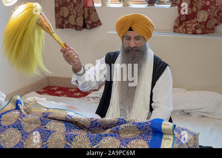 Ein Sikh Priester in einem turban liest aus dem Guru Granth Sahib heiligen Buch an einem Tempel in Richmond Hill, Queens, New York City. Stockfoto