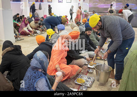 Ein Sikh-Mann serviert Sitzenden in einer Langar, einer kostenlosen Gemeinschaftsküche, Essen. In South Richmond Hill, Queens, New York City. Stockfoto