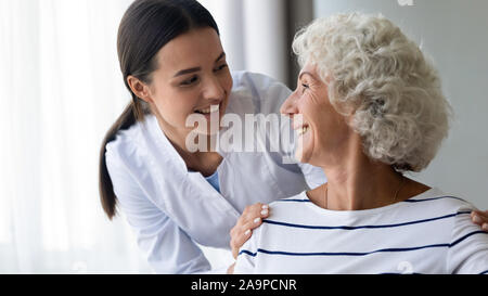 Pflege lächelnde junge Krankenschwester kümmert sich um ältere Oma patient Stockfoto