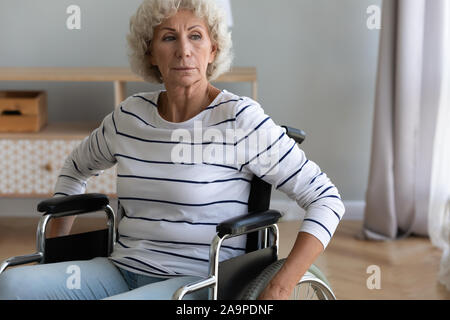 Traurig behinderte ältere Frau, die auf Rollstuhl zu Hause sitzen Stockfoto