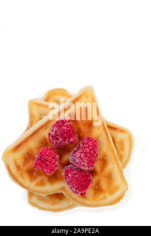 Herzförmige Plätzchen mit roten Beeren. Wiener Waffeln auf einem weißen Teller mit gefrorenen Himbeeren eingerichtet. Stockfoto