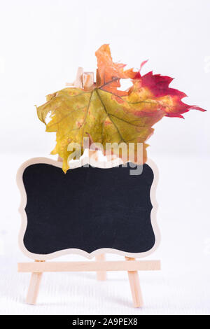 Leere Kreidetafel stand Mockup mit bunten Blatt ganz nah am weißen Stein Wand Hintergrund. Leere Straße Schilder oder Tischdekoration Tafel wi Stockfoto