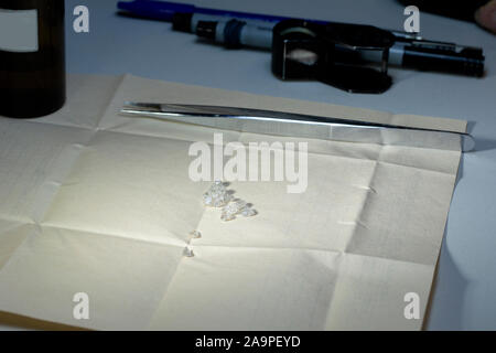 Schmuck Industrie. Diamanten auf Papier mit einer Lupe und Pinzette. Handvoll Edelsteine Stockfoto