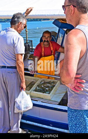 Frische Fische zum Verkauf direkt von einem kleinen Fischerboot, am Kai in der Hauptstadt Argostoli vertäut. Griechische Fischer mit Schnurrbart. Stockfoto