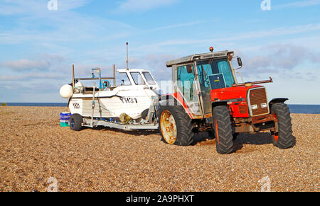 Ein Blick auf die Küstenfischerei Boot auf einem Anhänger mit Traktor auf der Kiesstrand in North Norfolk an cley-next-the-Sea, Norfolk, England, UK, Europa. Stockfoto