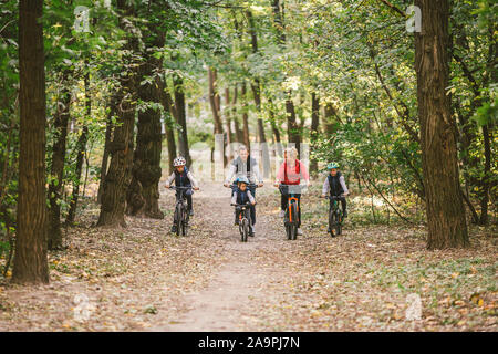 Eltern und Kinder zum Radfahren auf Waldweg. Junge Familie Radfahren im Herbst Park. Familie Mountainbiken auf Wald. Thema familie aktiv Sport im Freien Stockfoto