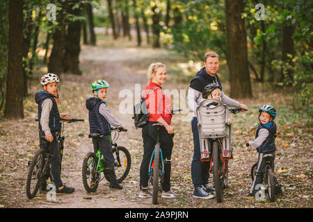 Eltern und Kinder zum Radfahren auf Forstweg. Familie in warme Kleidung radfahren Herbst Park. Familie Mountainbike auf Wald. active Sports Outdoor Recreation Stockfoto