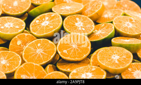 In Scheiben geschnittene orangen Hintergrund. Bunte orange Zitrusfrüchten Schichten. Die Hälfte orange Früchte, frisch und saftig. gesunde Ernährung und Vitamin C Stockfoto