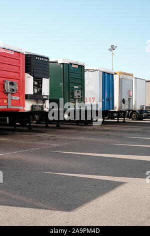 Eine Reihe von geparkten Lkw Anhänger mit Schatten und blauer Himmel - Nutzfahrzeuge - Lkw - Lastkraftwagen - LKW-Park - Geparkte große Nutzfahrzeuge - Ware depot Stockfoto