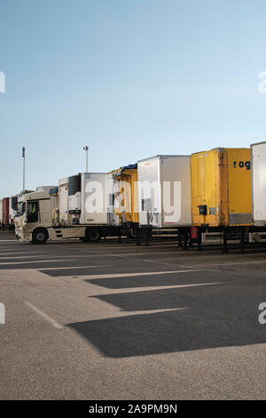 Eine Reihe von geparkten Lkw Anhänger mit Schatten und blauer Himmel - Nutzfahrzeuge - Lkw - Lastkraftwagen - LKW-Park - Geparkte große Nutzfahrzeuge - Ware depot Stockfoto