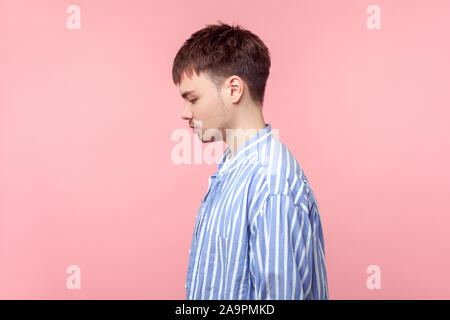 Seitenansicht Portrait von umgekippt braunhaarige Mann mit dem kleinen Bart und Schnurrbart in casual Striped Shirt ständigen Blick nach unten mit gesenktem Kopf, Depression. Stockfoto