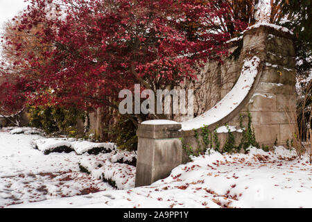 Alte Mauer aus Stein in einem Garten im Schnee Stockfoto