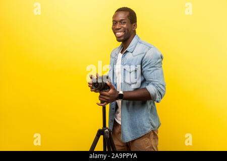 Portrait von Angeregten motivierte Fotografen oder Reisende in Jeans casual Shirt lächelnd und an der Kamera posieren mit professionellen digitalen DSLR-Kamera auf Tri Stockfoto