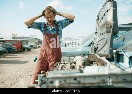 Wütend männlichen Handwerker arbeiten auf dem Auto junkyard Stockfoto