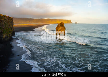 Sonnenuntergang am Strand und Kirkjufjara Arnardrangur Cliff. Atlantischen Ozean in der Nähe von Vik Dorf, Island. Malerische Bild des berühmten Touristenattraktion. Stockfoto