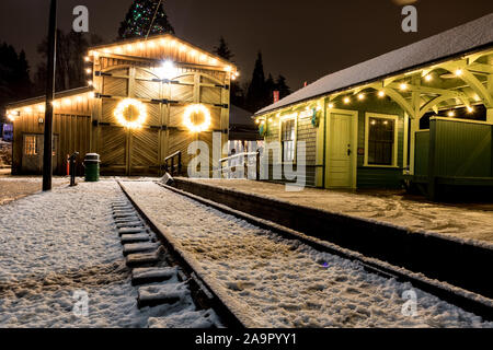 Barn House mit Weihnachtsbeleuchtung dekoriert in einer winternacht fotografiert, dieser Kranz hebt sich der verwitterte Holz- Hintergrund. Stockfoto