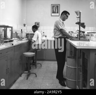 1960 s, historischen, chemische Forschung Wissenschaftler in einem Labor arbeiten, Saudi-Arabien. Ein umrahmtes Bild der Kronprinz ist an der Wand. Stockfoto