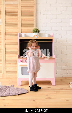 Kleines Kind Konzept. Adorable lächelnd Kleinkind Mädchen an Spielen Küche in hellen Zimmer Platz kopieren Stockfoto