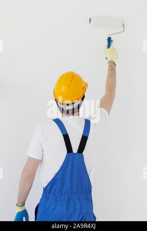 Männliche Arbeiter in Uniform malen Wände in neues Haus. Reparatur, Bau und Hypothek Konzept. Stockfoto