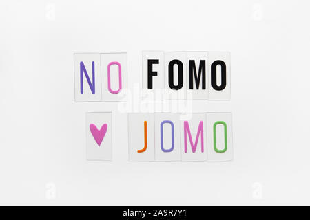 Abkürzung Worte FOMO, JOMO auf transparenten Kunststoff auf weißem Hintergrund. FOMO bedeutet Angst vor fehlenden heraus. JOMO - Freude fehlt. Opposition, Choic Stockfoto