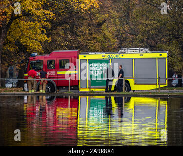 London, Großbritannien. 17. Nov 2019. Ein feuerwehrauto auf eine Pause erscheint auf dem Wasser zu schweben - Herbst Bäume spiegeln sich in den See zum Bootfahren auf Clapham Common, London. Credit: Guy Bell/Alamy leben Nachrichten Stockfoto
