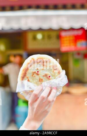 Hand mit traditionellen chinesischen Pfannkuchen bei Guandu antike Stadt in Kunming Stockfoto