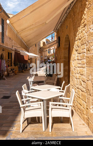 Mallorca, Spanien - Mai 10,2019: Tische und Stühle im Cafe auf der Straße in der Altstadt von Alcudia, Mallorca Stockfoto