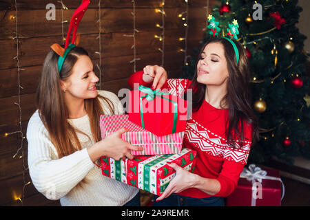 Zwei Freundinnen lachend und Weihnachtsgeschenke zu Hause Stockfoto