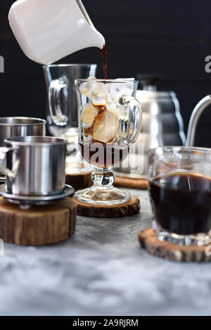 Die vietnamesischen Eiskaffee. Gießen schwarzen Kaffee in Glas mit Eiswürfeln auf dunklem Hintergrund Kopie Raum Stockfoto