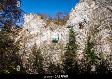 Seilbahn mit blauem Himmel und Felsen im Hintergrund. Kabel Kabine in Mähren. Macocha Kabel-Straßenbahn. Übersetzung von Text in Bild: Macocha Seilbahn. Stockfoto