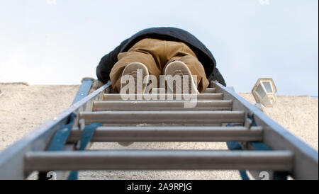 Low Angle View für einen Heimwerker Klettern auf einer Leiter. Stockfoto