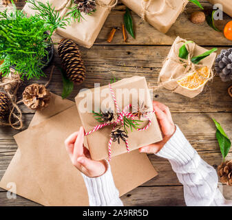 Frauen und Kinder Hände Weihnachten Geschenk Box dekorieren. Geschenke Sammlung im Vintage, rustikal, DIY-Stil. Weihnachten oder Silvester festliche Hintergrund fl Stockfoto