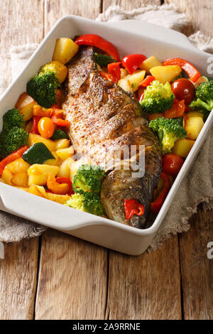 Fluss Fisch gebackene Karpfen mit Gemüse close-up in einer Auflaufform auf den Tisch. Vertikale Stockfoto