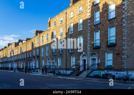 Terrasse der georgianischen Häuser mit Schatten Reflexion der gegenüberliegenden Terrasse. Architektonisches Detail mit Paar an einem sonnigen Tag in Dublin, Irland Stockfoto