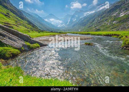 Üppige Tal mit Gletscherbach fließt aus dem schmelzenden Eis und Schnee auf die umliegenden Berge. Idyllische Berglandschaft. Stockfoto