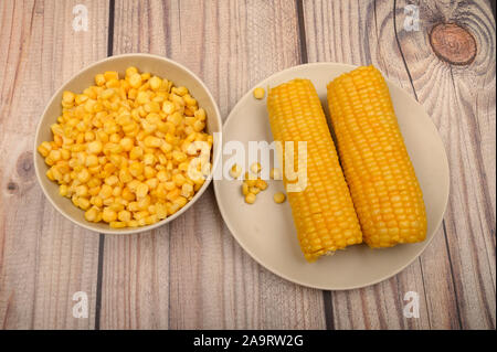 Zwei Ohren von gekochten Mais in eine Platte und ein Korn von Korn auf dem Tisch. Gesunde Ernährung. Fitness Ernährung. Für einen süßen Leckereien Stockfoto