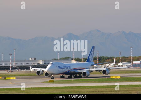 Mailand, Malpensa, Lombardei, Italien. Über 10/2019. Nippon Cargo Boeing 747 auf dem Flughafen Malpensa Landebahn. Im Hintergrund die Berge der Alp Stockfoto