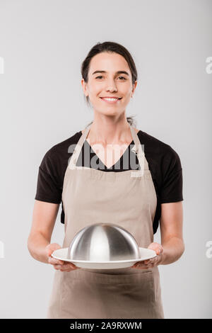 Glückliche junge Brünette Kellnerin holding Cloche mit zubereitete Speisen für Client Stockfoto