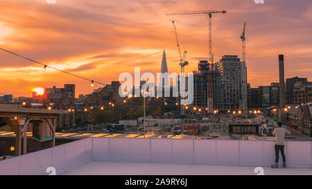 Tabak Dock, London, Großbritannien, 17. November 2019. Skating bei Sonnenuntergang. Die Menschen genießen Sie den spektakulären Blick über die Stadt London in der Londoner trendy Oberlicht Eisbahn, einer Dachterrasse am historischen Tabak Dock Komplex in Wapping, East London. Credit: Imageplotter/Alamy leben Nachrichten Stockfoto