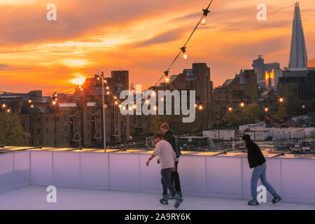 Tabak Dock, London, Großbritannien, 17. November 2019. Skating bei Sonnenuntergang. Die Menschen genießen Sie den spektakulären Blick über die Stadt London in der Londoner trendy Oberlicht Eisbahn, einer Dachterrasse am historischen Tabak Dock Komplex in Wapping, East London. Credit: Imageplotter/Alamy leben Nachrichten Stockfoto